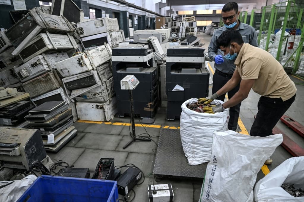คนงานกำลังชั่งน้ำหนักชิ้นส่วนอิเล็กทรอนิกส์ที่ถูกรื้อแยก ที่บริษัท “Ecowork” โรงงานรีไซเคิลขยะอิเล็กทรอนิกส์ ในเมืองกาซิอาบาด ประเทศอินเดีย