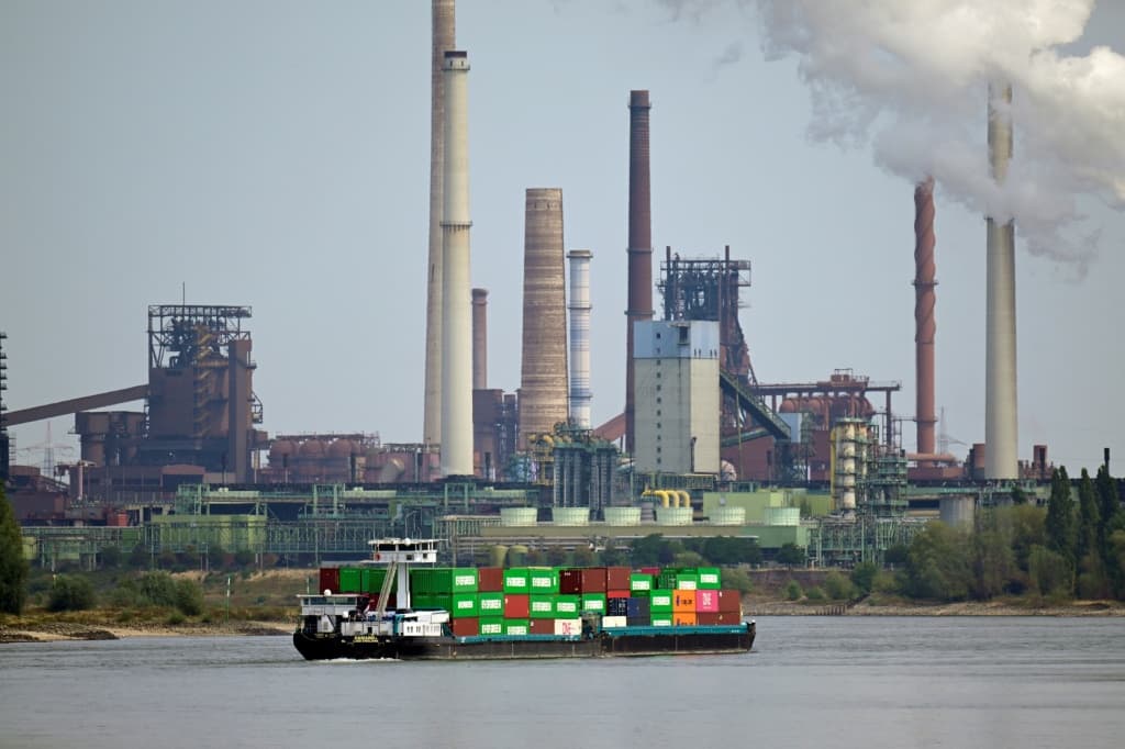 เรือบรรทุกตู้สินค้าลำหนึ่งแล่นผ่านบริษัท Thyssenkrupp Steel Europe AG ในเมืองดุยส์บวร์ก บนแม่น้ำไรน์