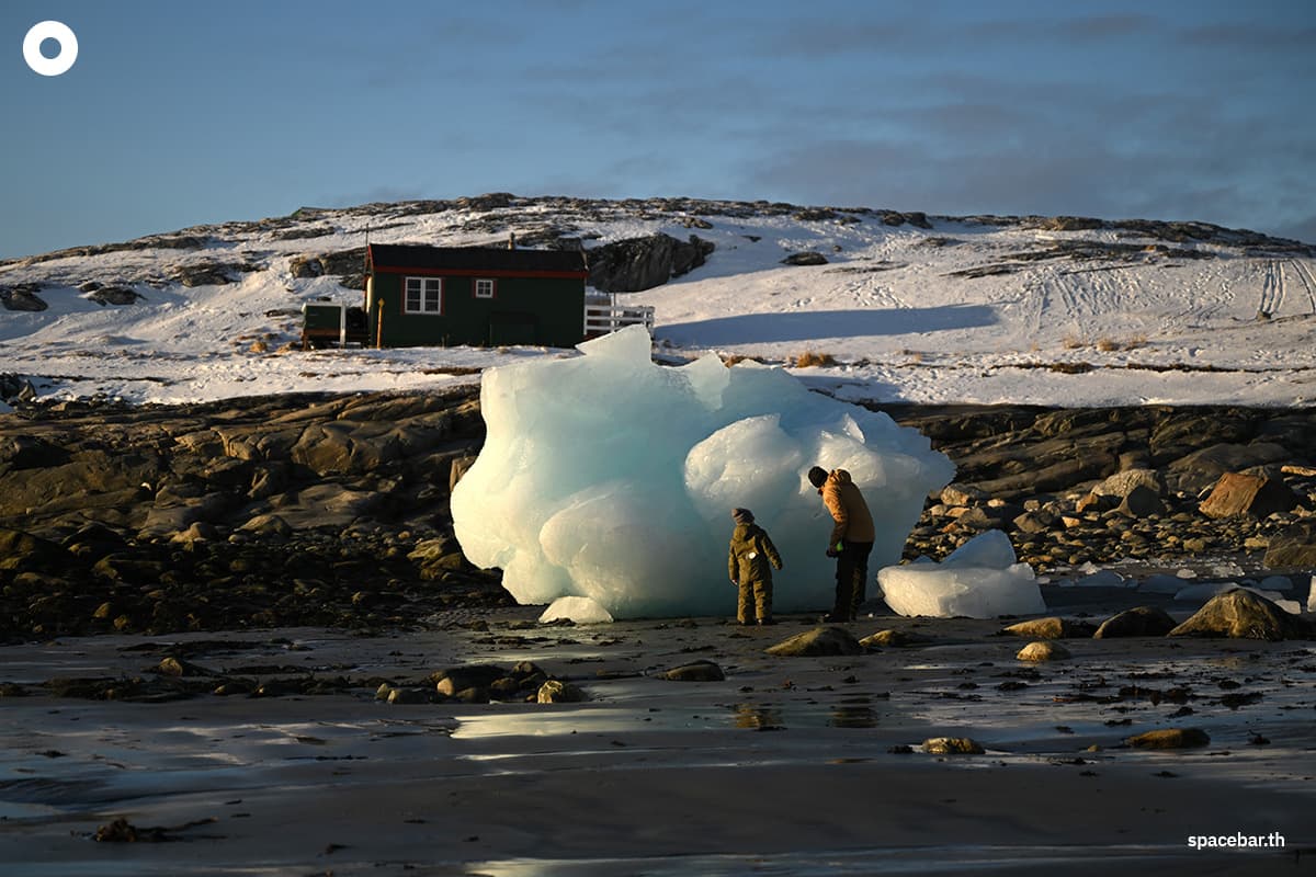 พ่อและลูกชายมองดูแท่งน้ำแข็งขนาดใหญ่ริมชายฝั่งทางตะวันตกของกรีนแลนด์ เมื่อวันที่ 4 กุมภาพันธ์ 2026 (ภาพโดย อินา ฟาสเบนเดอร์ / เอเอฟพี)