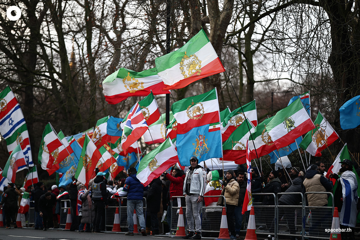 PhotoStory- ผู้ประท้วงต่อต้านระบอบอิหร่านโบกธงชาติอิหร่านก่อนการปฏิวัติปี 1979 ซึ่งมีสัญลักษณ์สิงโตและดวงอาทิตย์ และโบกธงชาติอิสราเอลระหว่างการชุมนุมนอกสถานทูตอิหร่าน ใจกลางกรุงลอนดอน เมื่อวันที่ 9 มกราคม 2026 (Photo by HENRY NICHOLLS / AFP)