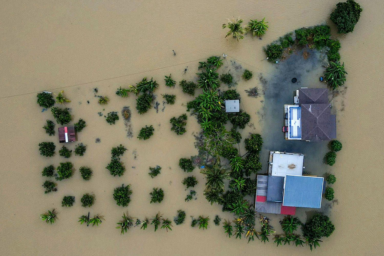 PhotoStory- ภาพมุมสูงเผยให้เห็นบ้านเรือนที่ถูกน้ำท่วมล้อมรอบในเมืองกังการ์ รัฐเปอร์ลิส ทางตอนเหนือของมาเลเซีย เมื่อวันที่ 27 พฤศจิกายน 2025 (Photo by MOHD RASFAN / AFP)