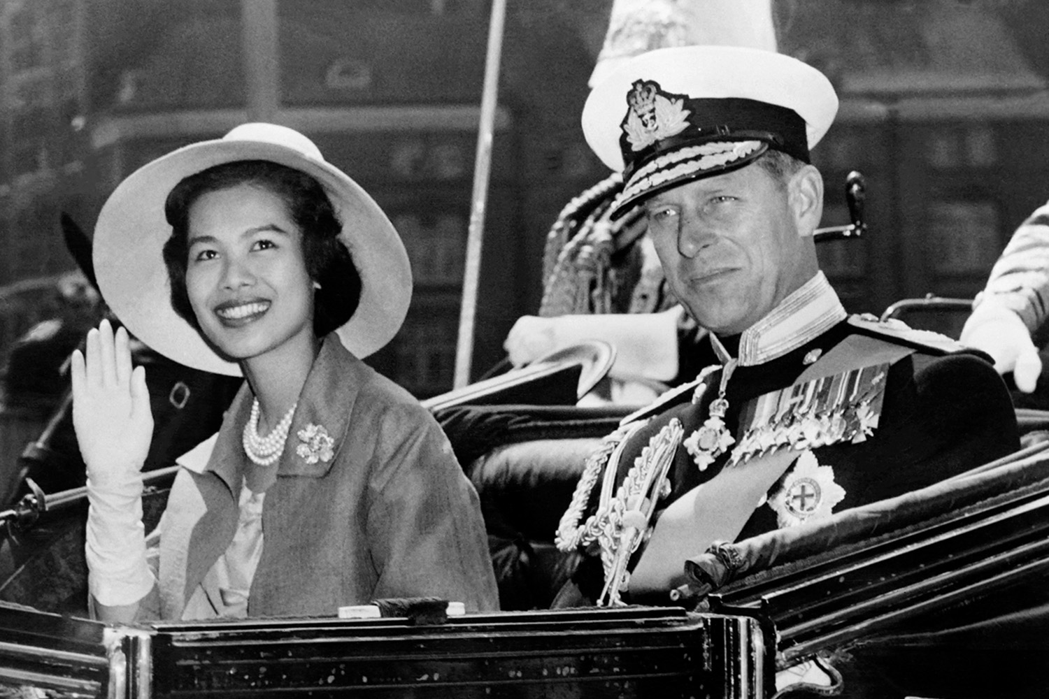 PhotoStory-   สมเด็จพระนางเจ้าสิริกิติ์ พระบรมราชินีนาถ พระบรมราชชนนีพันปีหลวง ทรงแย้มพระสรวลขณะทรงโบกพระหัตถ์ร่วมกับเจ้าชายฟิลิป ดยุกแห่งเอดินบะระ ในเดือนกรกฎาคม 1960 (Photo by CENTRAL PRESS / AFP) 