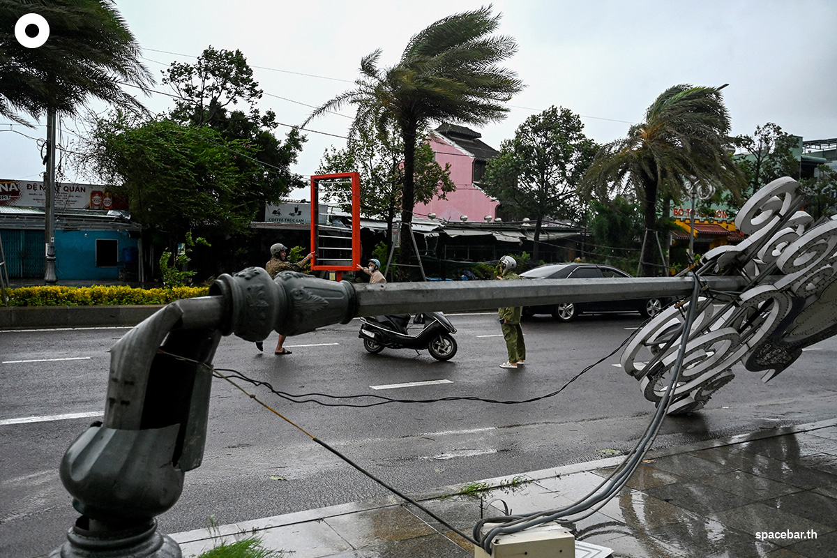 PhotoStory-   ชาวบ้านเดินผ่านเสาไฟที่หักโค่นลงจากลมแรงก่อนที่พายุไต้ฝุ่นคัลแมกีจะพัดเข้าจังหวัดซาลาย ทางตอนกลางของเวียดนามในวันที่ 6 พฤศจิกายน 2025 (Photo by NHAC NGUYEN / AFP)   