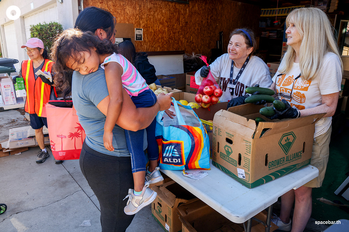 PhotoStory-   หญิงคนหนึ่งอุ้มลูกสาวที่กำลังหลับมารับอาหารฟรีจากธนาคารอาหาร (Feeding San Diego) เมื่อวันที่ 24 ตุลาคม 2025 ในเมืองซานดิเอโก รัฐแคลิฟอร์เนีย (Photo by SANDY HUFFAKER / AFP) 